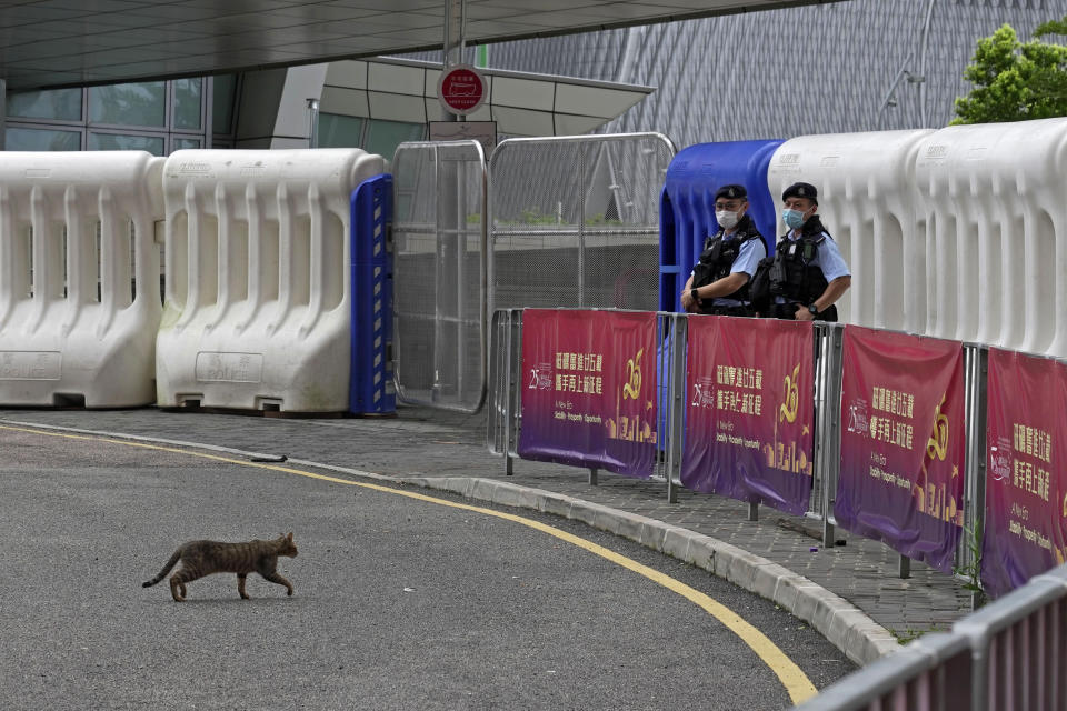 A cat crosses a road as police officers stand guard outside the high speed train station for the Chinese president Xi Jinping's visit to mark the 25th anniversary of Hong Kong handover to China, in Hong Kong, Thursday, June 30, 2022. (AP Photo/Kin Cheung)