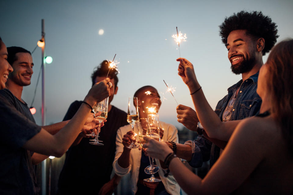 Friends happily drinking together while lighting sparklers