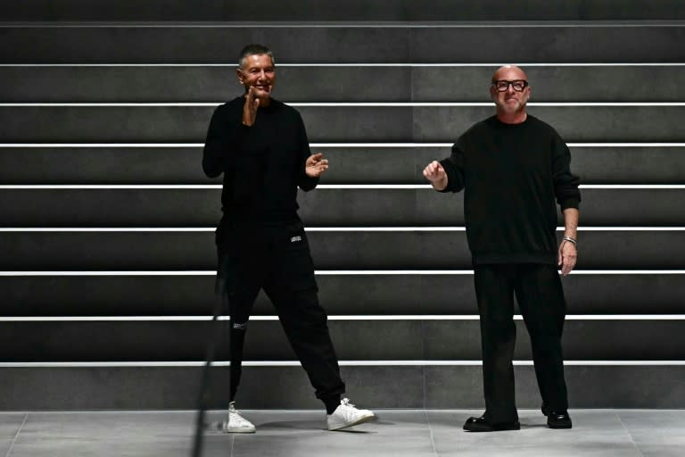 Domenico Dolce (D) et Stefano Gabbana (G) saluent le public après un défilé à Milan, le 13 janvier 2024 (GABRIEL BOUYS)