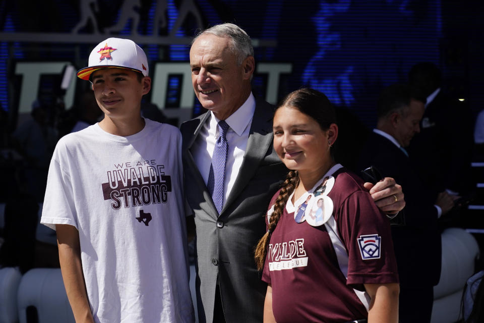 MLB Commissioner Rob Manfred, center, poses for photos with Aidan, left, and Willa Suarez, of Uvalde, Tex., during the 2022 MLB baseball draft, Sunday, July 17, 2022, in Los Angeles. (AP Photo/Jae C. Hong)
