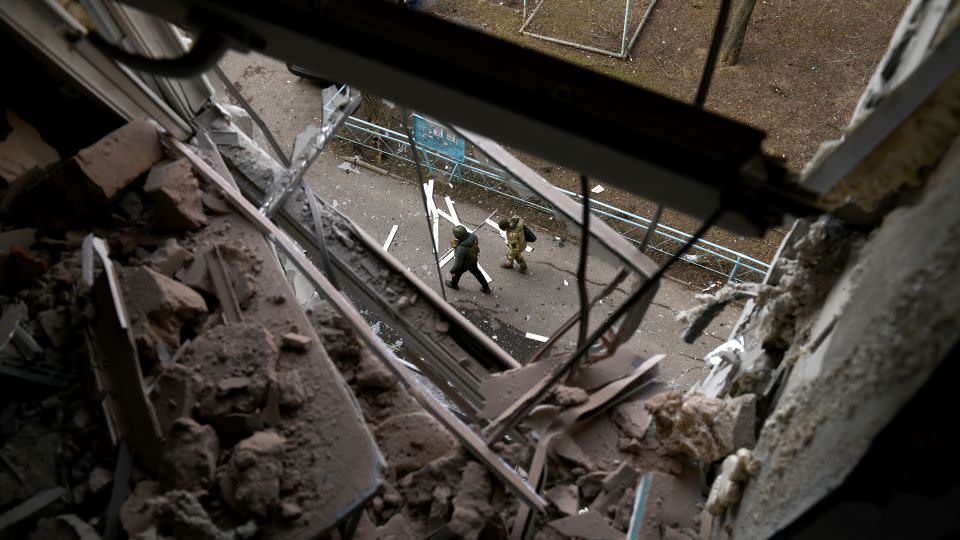 افسران اجرای قانون از کنار ساختمانی که در نتیجه گلوله باران در دونتسک آسیب دیده است عبور می کنند.  - Stringer/AFP/Getty Images