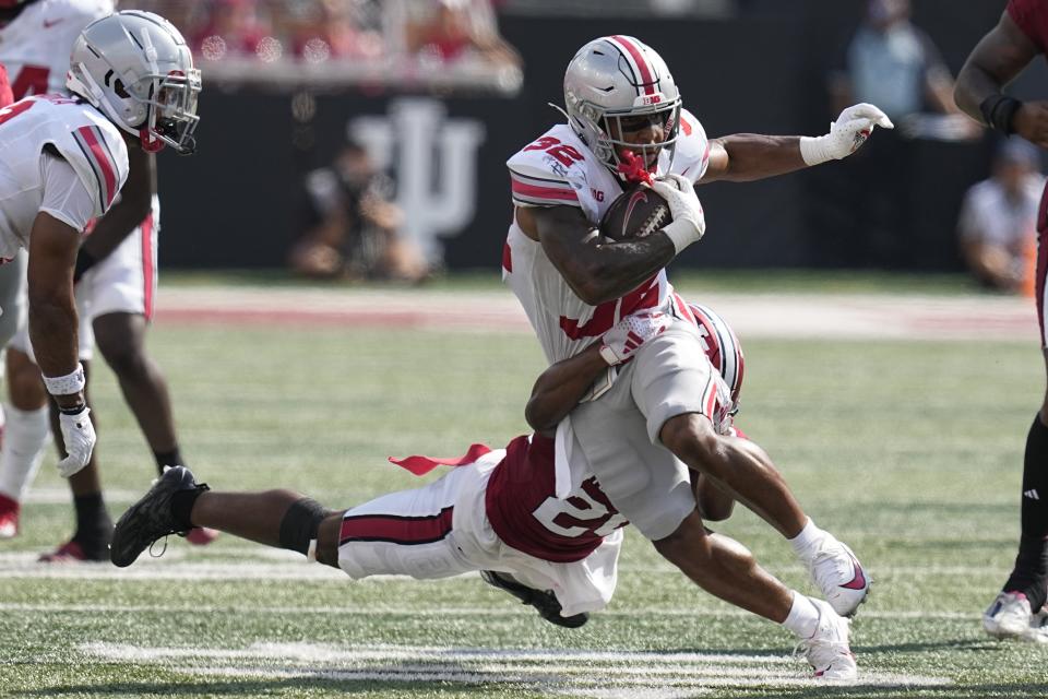 Ohio State running back TreVeyon Henderson (32) is tackled by Indiana defensive back Louis Moore during the first half of an NCAA college football game, Saturday, Sept. 2, 2023, in Bloomington, Ind. (AP Photo/Darron Cummings)