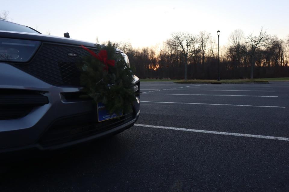 Police escort car sits in the parking lot with a wreath on the front