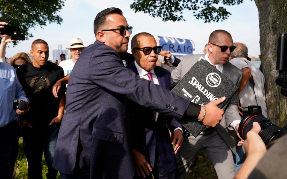 A security detail escorts former Detroit Police Chief James Craig from protesters before he could officially announce his run for Michigan governor as a Republican candidate on Sept. 14, 2021 from Belle Isle.