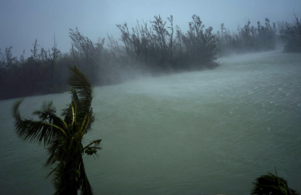 Strong winds from Hurricane Dorian blow the tops of trees and brush while whisking up water from the surface of a canal that leads to the sea, located behind the brush at top, seen from the balcony of a hotel in Freeport, Grand Bahama, Bahamas, Monday, Sept. 2, 2019. Hurricane Dorian hovered over the Bahamas on Monday, pummeling the islands with a fearsome Category 4 assault that forced even rescue crews to take shelter until the onslaught passes. (AP Photo/Ramon Espinosa)