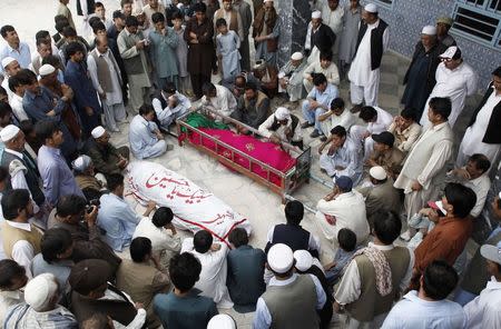 Shi'ite Muslim men from Pakistan's ethnic Hazara minority sit as they mourn beside the coffins of their relatives, who were killed after gunmen opened fire on a bus, during a funeral ceremony in Quetta October 23, 2014. REUTERS/Naseer Ahmed