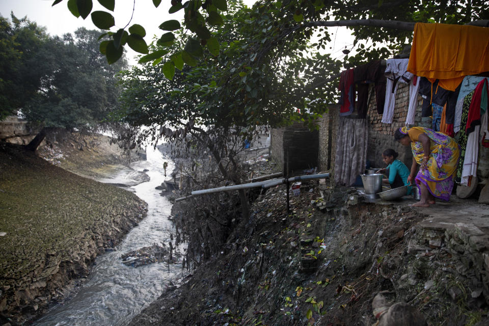 Women wash their household items by a drainage flowing into the river Ganges in Varanasi, one of the Hinduism's holiest cities, in the northern Indian state of Uttar Pradesh, Friday, Oct. 18, 2019. For millions of Hindus, Varanasi is a place of pilgrimage and anyone who dies in the city or is cremated on its ghats is believed to attain salvation and freed from the cycle of birth and death. Tens of thousands of corpses are cremated in the city each year, leaving half-burnt flesh, dead bodies and ash floating in the Ganges. (AP Photo/Altaf Qadri)