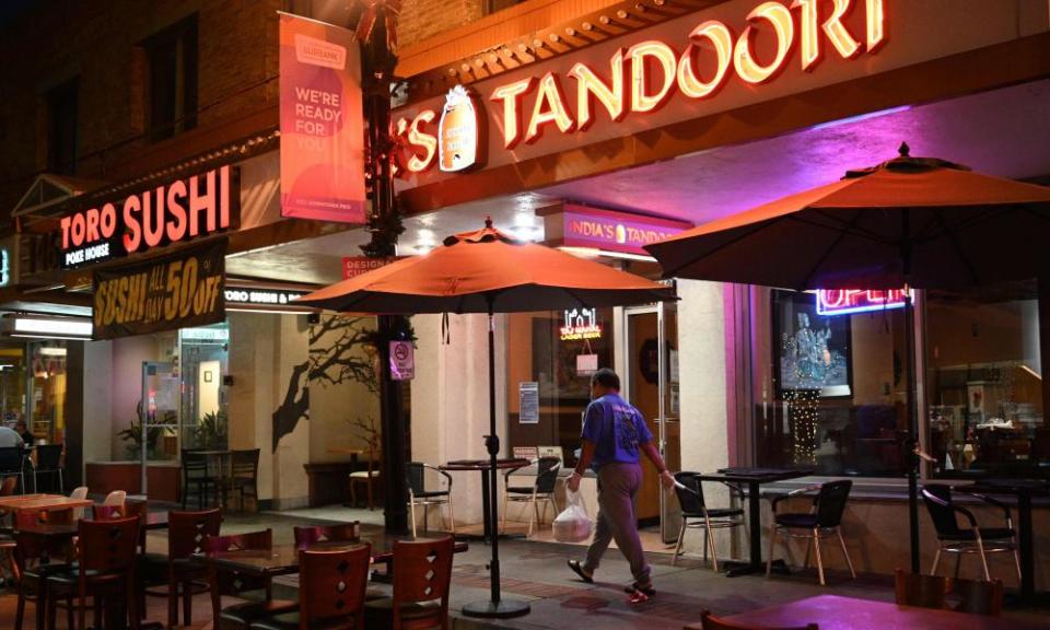 A man carries a package of take-out food as he walks past temporary outdoor restaurant seating last month in Burbank.