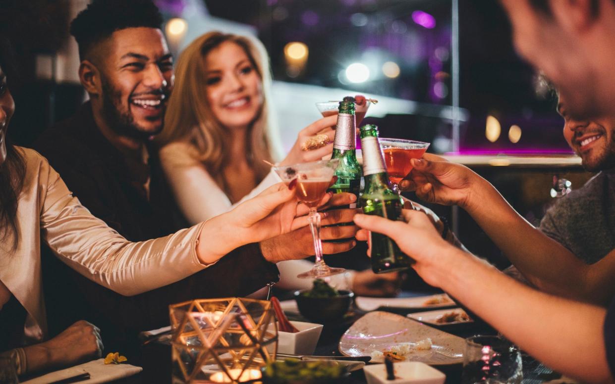 Group of friends clinking glasses while enjoying an evening meal in a restaurant on New Years Eve