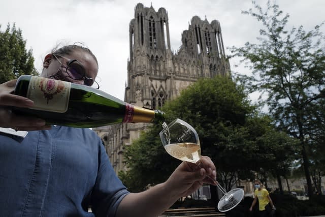 A waitress serves a glass of champagne at La Grande Georgette restaurant in front of the cathedral in Reims, in the Champagne region (Francois Mori/AP)