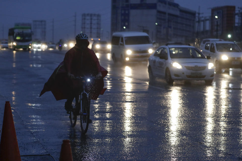 A man ina. raincoat rides his bicycle during heavy rains from Typhoon Vamco in Quezon city, Philippines on Wednesday, Nov. 11, 2020. Typhoon Vamco blew closer Wednesday to a northeastern Philippine region still struggling to recover from a powerful storm that left a trail of death and destruction just over a week ago, officials said, adding that thousands of villagers were being evacuated again to safety. (AP Photo/Aaron Favila)