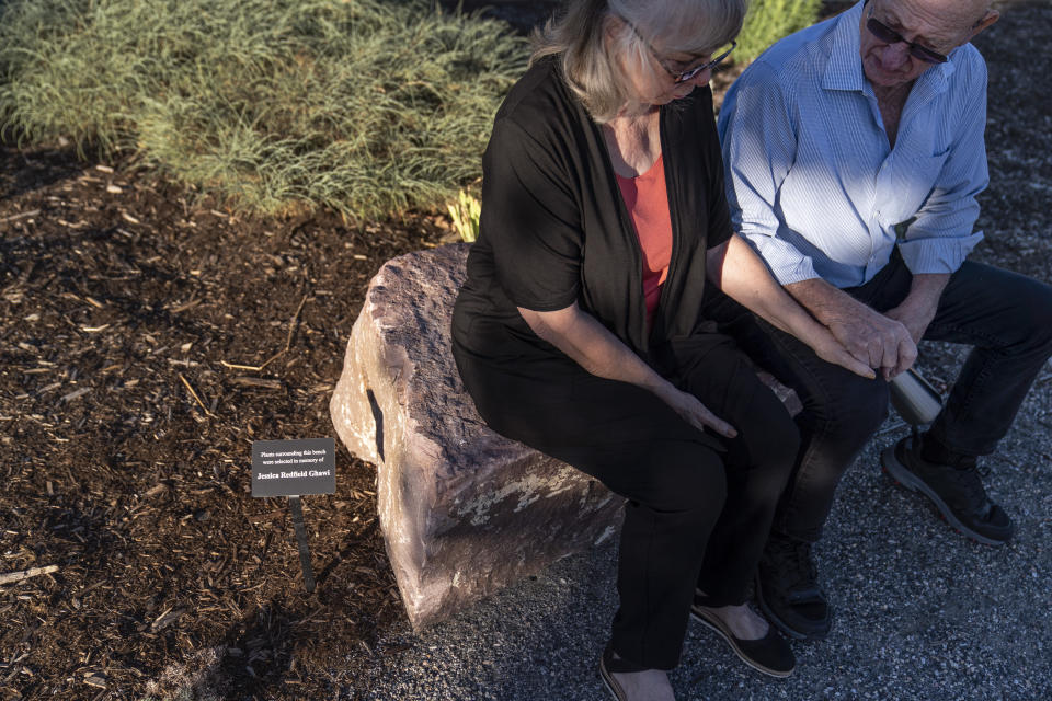 Sandy Phillips, left, and her husband, Lonnie, sit on a rock dedicated to Sandy’s daughter, Jessica Ghawi, one of 12 people killed in the 2012 mass shooting at an Aurora, Colo., movie theater, as they visit a memorial to the victims Tuesday, Sept. 5, 2023, in Aurora. Suffering through their own personal loss, the couple set out to help other parents like them, traveling to shooting sites around the country. The trip continued for a decade. (AP Photo/David Goldman)