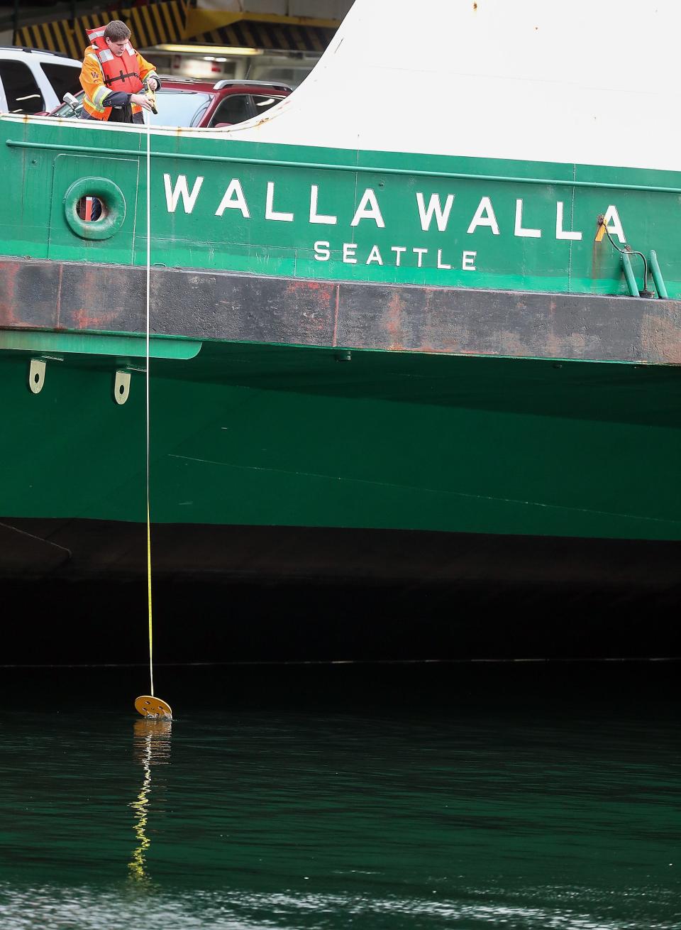 A Washington State Ferries crew member checks the depth of the water from the car deck of the Walla Walla after it ran aground while transiting Rich Passage and ended up on the shore near Lynwood Center on Bainbridge Island, Wash. on Saturday, April 15, 2023.