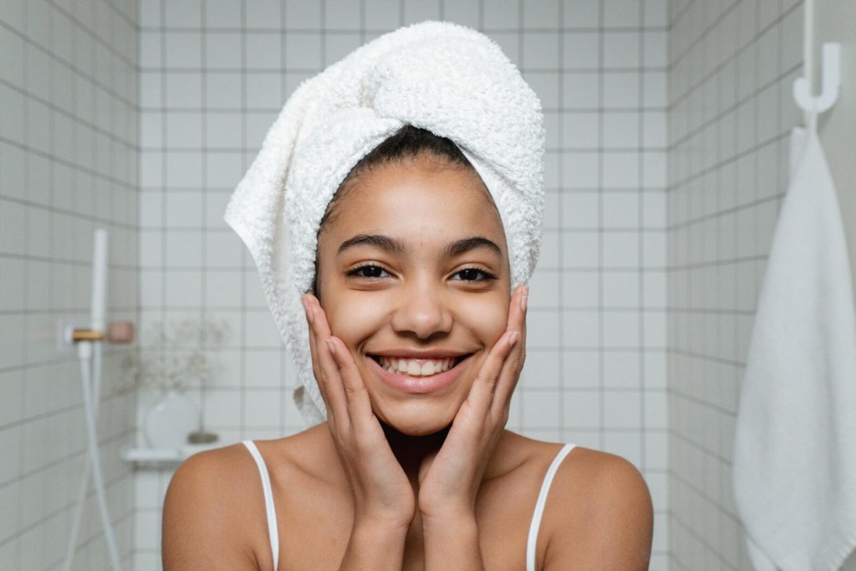 woman holding face wearing towel on head