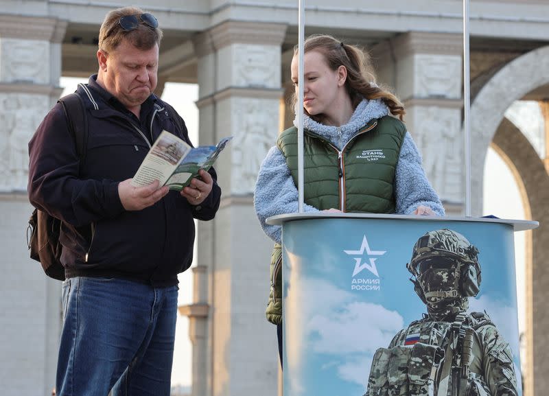 FILE PHOTO: A man studies a leaflet promoting Russian army service in Moscow