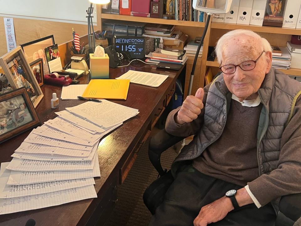 Markoff sitting at his desk, holding his thumb up at the camera.