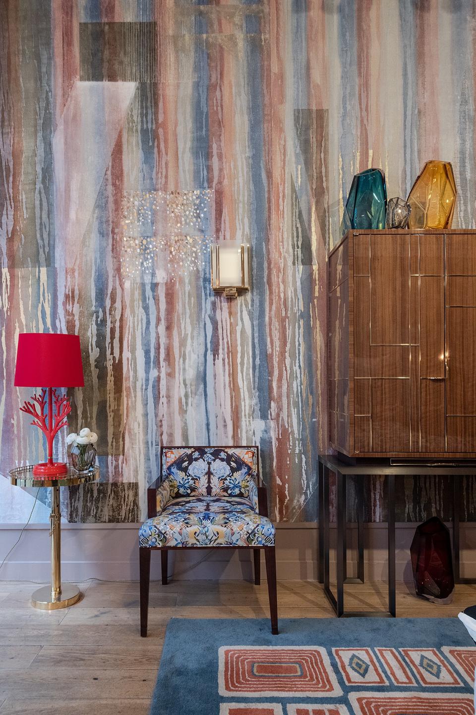 The scene at Ancien et Moderne: Wallcovering by Fromental, coral lamps by Hector Finch, a chair covered in Voutsa fabric, and a rug by Maison Leleu.