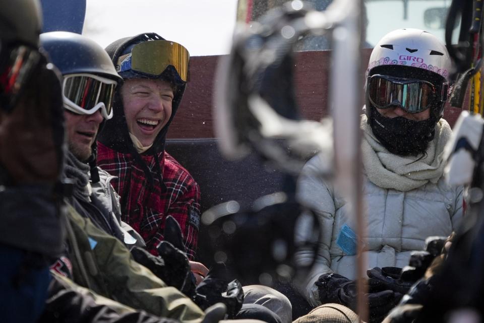 Riders laugh as they are towed up a ski hill in a trailer retrofitted with old bus seats at Parker-Fitzgerald Cuchara Mountain Park on Sunday, March 19, 2023, near Cuchara, Colo. Some communities including Cuchara are now finding a niche, offering an alternative to endless lift lines and sky-high ticket prices. They're reopening, several as nonprofits, offering a mom-and-pop experience at a far lower cost than mountains run by corporate conglomerates. (AP Photo/Brittany Peterson)