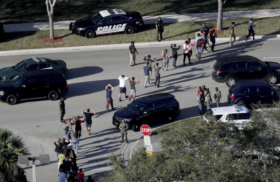 FILE - Students hold their hands in the air as they are evacuated by police from Marjory Stoneman Douglas High School, Wednesday, Feb. 14, 2018, in Parkland, Fla., after a shooter opened fire on the campus. (Mike Stocker/South Florida Sun-Sentinel via AP, File)