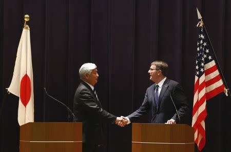 Japan's Defense Minister Gen Nakatani (L) and U.S. Secretary of Defense Ash Carter shake hands after a news conference at the defense ministry in Tokyo April 8, 2015. REUTERS/Thomas Peter