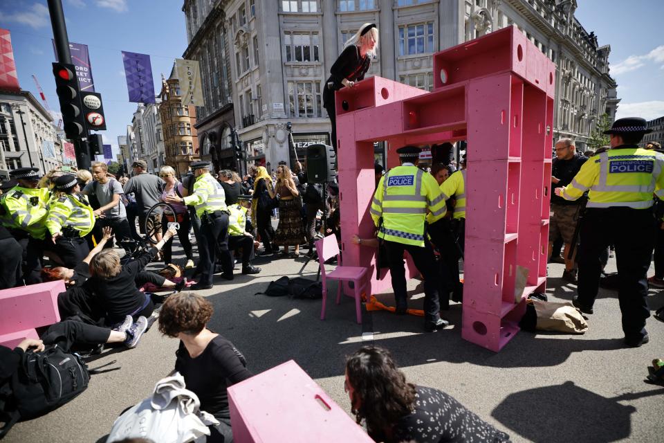 Police officers arrive as climate activists from the Extinction Rebellion group build a structure and set up lock-on devices blocking the road in the middle of Oxford Circus in central London on August 25, 2021 during the group's 'Impossible Rebellion' series of actions. - Climate change demonstrators from environmental activist group Extinction Rebellion continued with their latest round of protests in central London, promising two weeks of disruption. (Photo by Tolga Akmen / AFP) (Photo by TOLGA AKMEN/AFP via Getty Images)