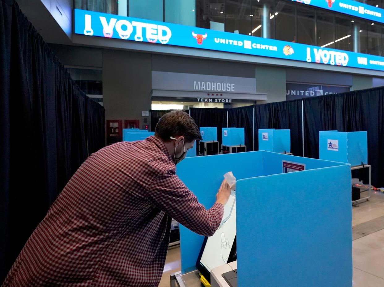 Chris Levine cleans an electronic voting screen on Election Day, Tuesday, Nov. 3, 2020, at the United Center, home of the Chicago's Blackhawks and Bulls professional sports franchises and transformed into a super voting site in Chicago.