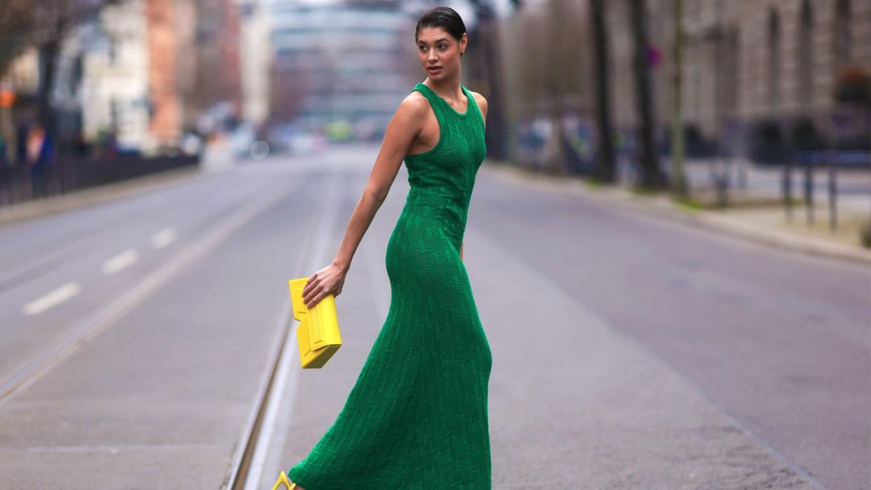 a woman in a green dress walking down a street