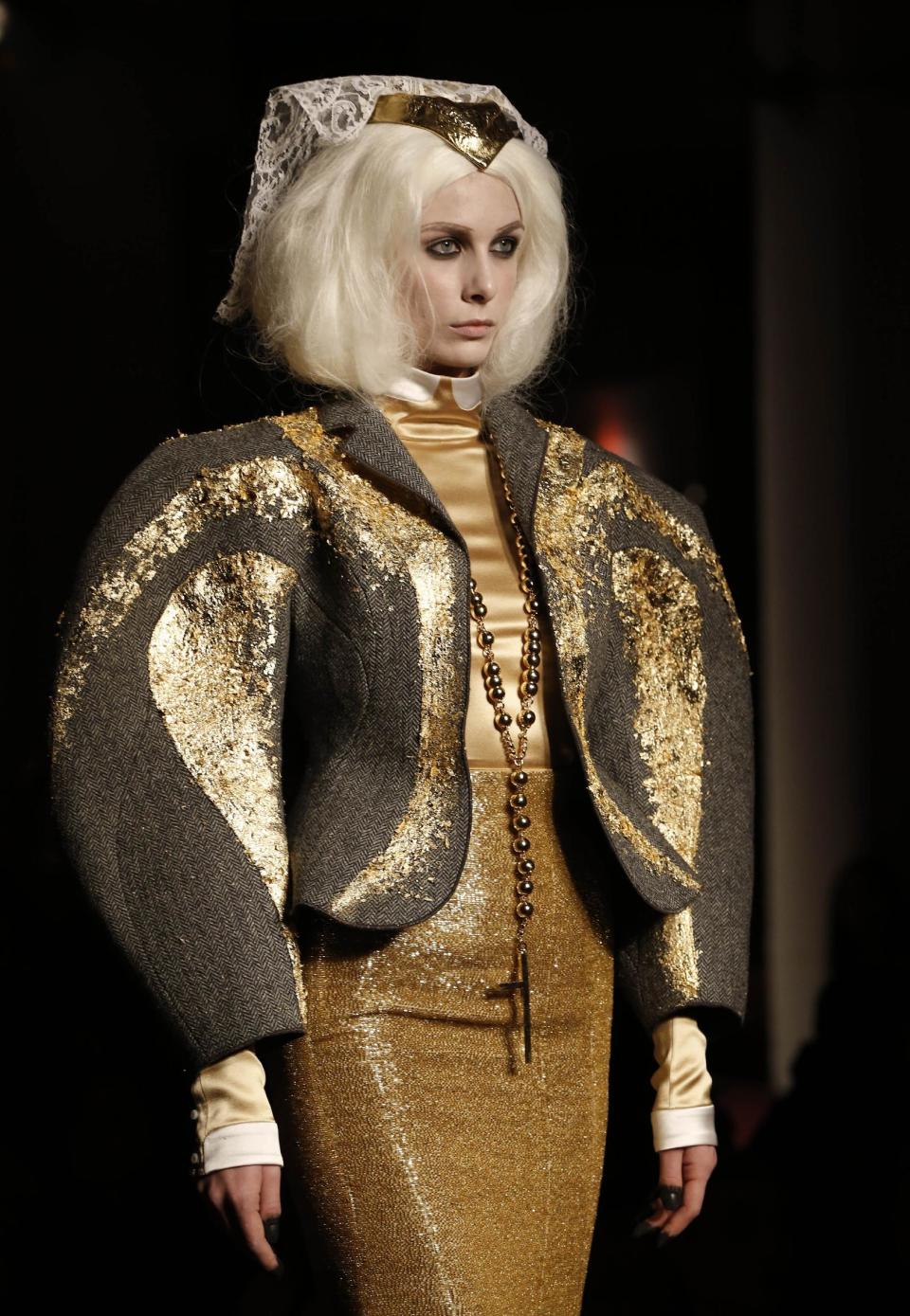 A model walks the runway in a jacket covered in gold leaf during the presentation of the Thom Browne Fall 2014 collection in New York, Monday, Feb. 10, 2014. (AP Photo/Kathy Willens)