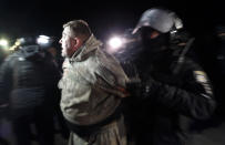 A Ukrainian riot police officer detains a protester, who planned to stop buses carrying passengers evacuated from the Chinese city of Wuhan, outside Novi Sarzhany, Ukraine, Thursday, Feb. 20, 2020. Several hundred residents in Ukraine's Poltava region protested to stop officials from quarantining the evacuees in their village because they feared becoming infected. Demonstrators put up road blocks and burned tires, while Ukrainian media reported that there were clashes with police, and more than 10 people were detained. (AP Photo/Efrem Lukatsky)