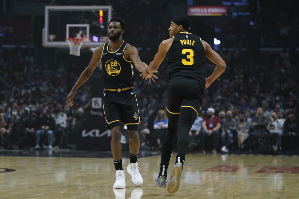 Golden State Warriors forward Andrew Wiggins (22) celebrates with guard Jordan Poole (3) after a point during the first half of an NBA basketball game against the Los Angeles Clippers in Los Angeles, Sunday, Nov. 28, 2021. (AP Photo/Ashley Landis)