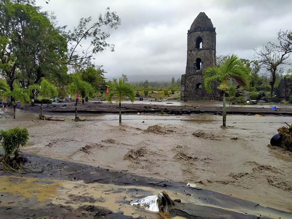 Floodwaters pass by Cagsawa ruins, a famous tourist spot in Daraga, Albay province, central Philippines as Typhoon Goni hit the area Sunday, Nov. 1, 2020. The super typhoon slammed into the eastern Philippines with ferocious winds early Sunday and about a million people have been evacuated in its projected path, including in the capital where the main international airport was ordered closed. (AP Photo/Alejandro Miraflor)