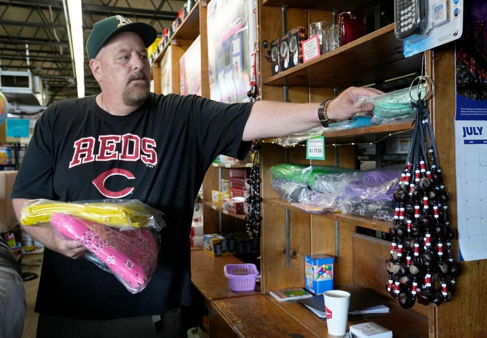 Tim Rohrbacher grabs colorful bandanas for a customer while working behind the counter at Star Beacon Products in Grandview Heights on Tuesday.