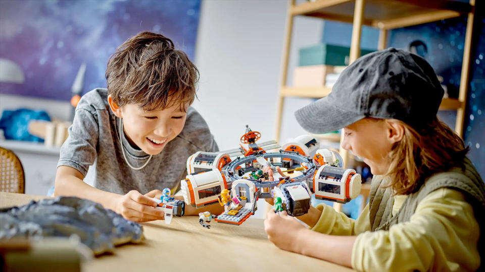 a young boy and a young girl play with legos on a wooden table