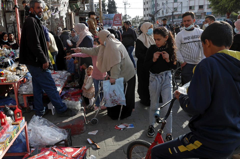 People, some wearing masks to help prevent the spread of the coronavirus, shop for the Muslim holy month of Ramadan, at the main market in Gaza City, Sunday, April 11, 2021. More than a year into the coronavirus pandemic, the worst fears are now coming true in the crowded, blockaded Gaza Strip: A sudden surge in infections and deaths is threatening to overwhelm hospitals weakened by years of conflict and Israeli border closures. (AP Photo/Adel Hana)