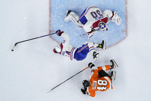 Montreal Canadiens' Jordan Harris, center, collides with Philadelphia Flyers' Morgan Frost, bottom, and Cayden Primeau during the second period of an NHL hockey game, Tuesday, March 28, 2023, in Philadelphia. (AP Photo/Matt Slocum)