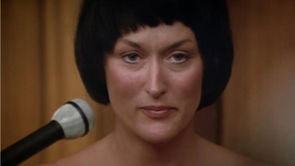 Meryl Streep, with short black hair, sits in court in the movie A Cry in the Dark