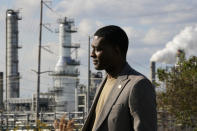 FILE - EPA Administrator Michael Regan stands near the Marathon Petroleum Refinery as he conducts a television interview, while touring neighborhoods that abut the refinery, in Reserve, La., Nov. 16, 2021. Regan announced the creation of a new office at EPA focused on environmental justice. "We are embedding environmental justice and civil rights into the DNA of EPA," Regan said. (AP Photo/Gerald Herbert)