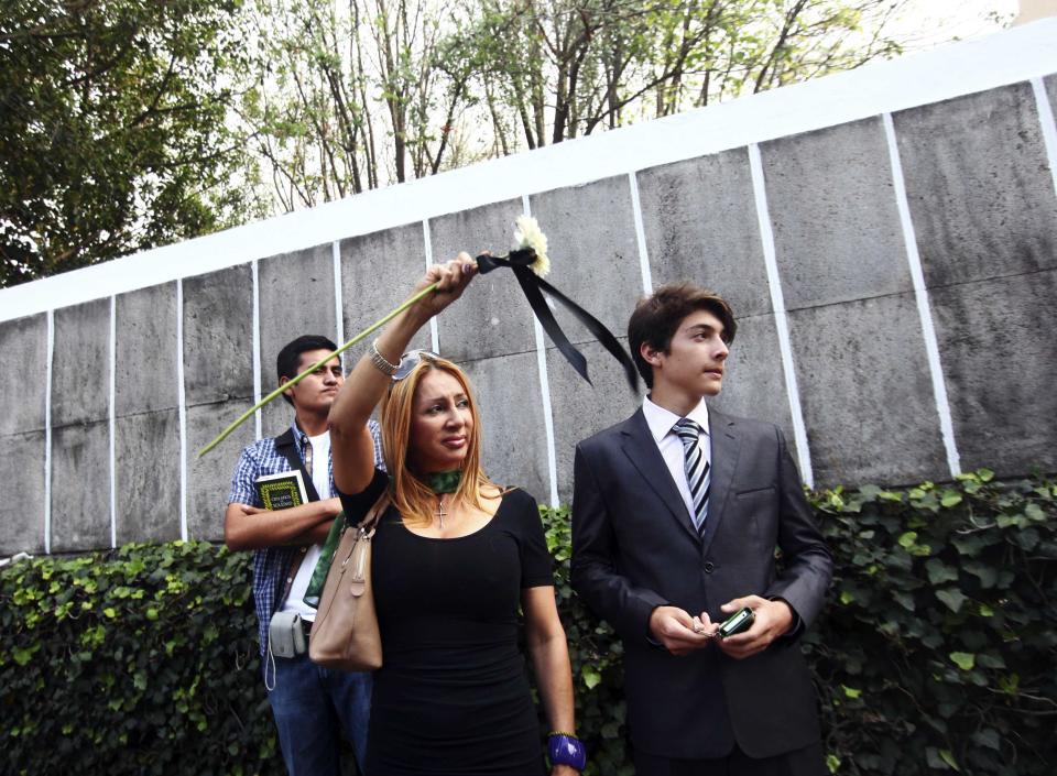 A woman waves a flower with a black ribbon while standing with others outside the home of Colombian Nobel Prize laureate Gabriel Garcia Marquez in Mexico City