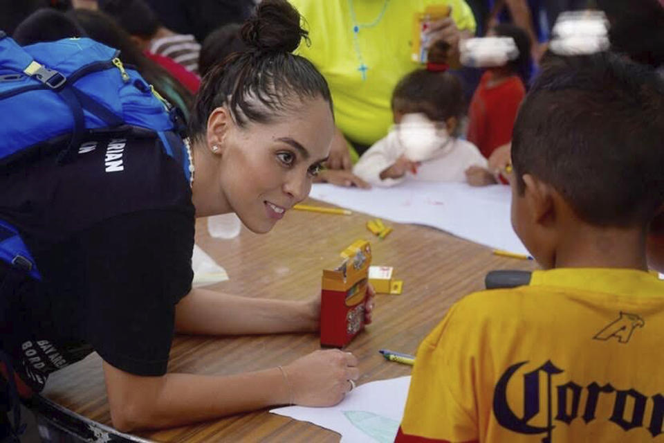 In this October 2019 photo provided by Pocho Sanchez, Daniela Dominguez, assistant professor in counseling psychology at University of San Francisco, draws and chats with children from Honduras at a migrant camp in Matamoros, Mexico. Dominguez said mutual aid networks are part of the Latino culture where people may feel safer getting help from their own community rather than government entities or formal charities. (Pocho Sanchez via AP)