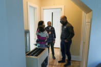 Thuy Do, left, and her husband, Jesse Robbins, right, talk with Abdul, center, Monday, Sept. 20, 2021, about a minor plumbing issue in the vacant rental home owned by the couple that they have provided Abdul — who worked as a mechanic before leaving Kabul, Afghanistan about a month ago — as a place to live with his family until they can find more permanent housing. Do was nine years old when her family arrived in the United States from Vietnam in the 1980s, and that memory led Do and Robbins to reach out to assist Afghans fleeing their country. (AP Photo/Ted S. Warren)