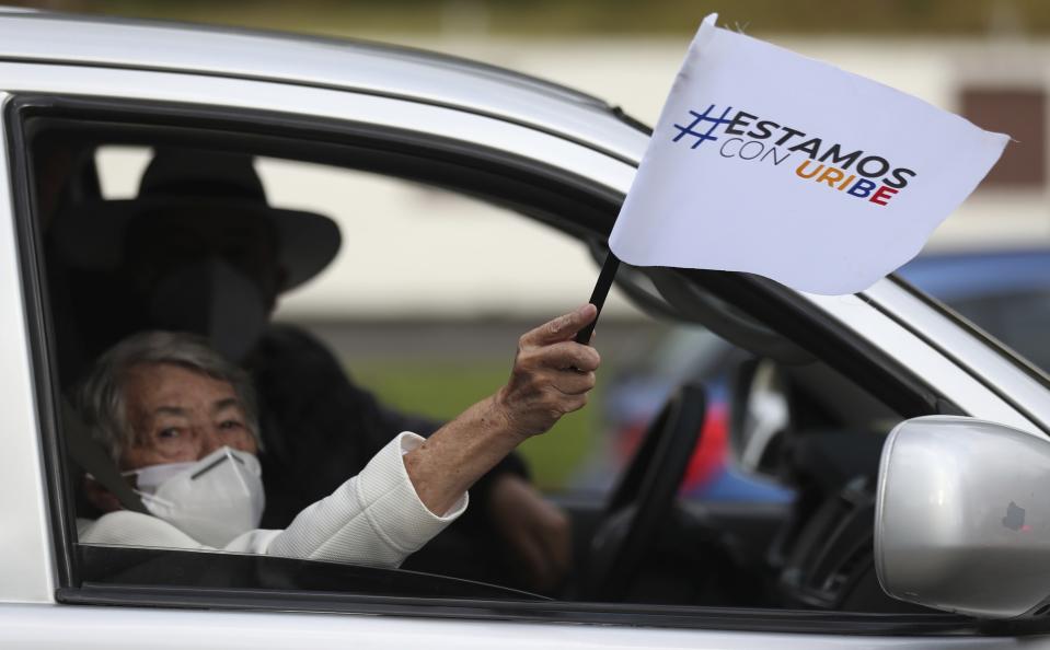 Un simpatizante del expresidente Álvaro Uribe sostiene un banderín con su nombre mientras participa en una caravana para protestar contra una decisión de la Corte Suprema que le impuso prisión domiciliaria mientras lo investiga por supuesta manipulación de testigos en Bogotá, Colombia, el viernes 7 de agosto de 2020. (AP Foto/Fernando Vergara)