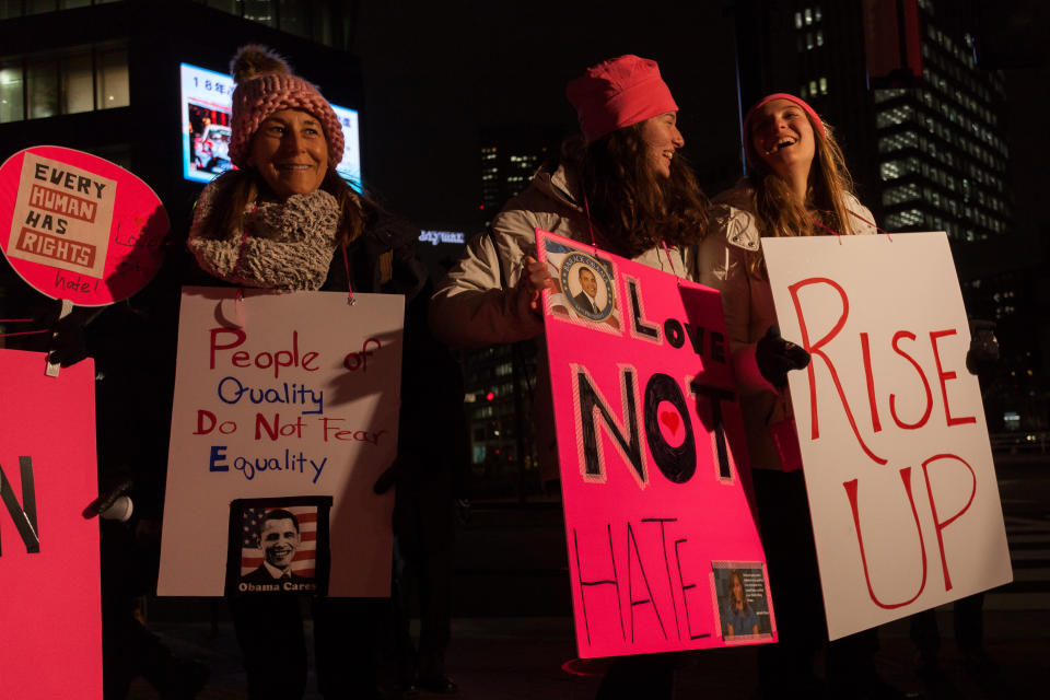 Women wearing pink hats to protest Trump's pussy grabbing comment hold signs before taking part in a protest march by members of the Democratic Party Abroad organization to mark the inauguration of President Donald Trump, on January 20, 2017 in Tokyo, Japan. Around 400 people took part in the march to honor the service given by President Obama and to protest against the policies expected of the new administration of President Trump.