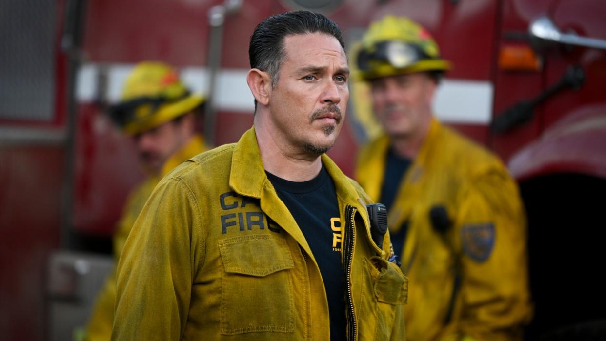  Kevin Alejandro as Manny standing in front of a fire truck in Season 2 of Fire Country. 