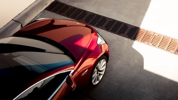 A red Tesla Model 3, seen from above.