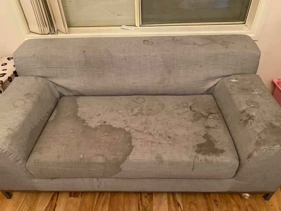 A very dirty and stained couch inside a children's playroom