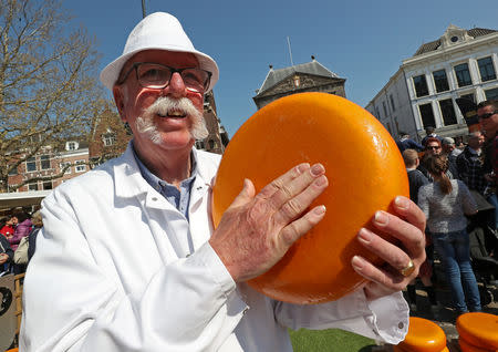 A seller holds a piece of Gouda cheese at the cheese market in Gouda, Netherlands April 18, 2019. REUTERS/Yves Herman