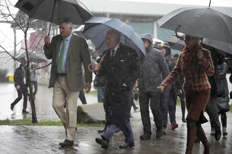 Britain's King Charles III, center, visits the Brodowin organic farm during a thunderstorm, in the village of Brodowin, about 80 kilometers, 50 miles, northeast of Berlin, Thursday, March 30, 2023. King Charles III arrived Wednesday for a three-day official visit to Germany. (AP Photo/Matthias Schrader, Pool)