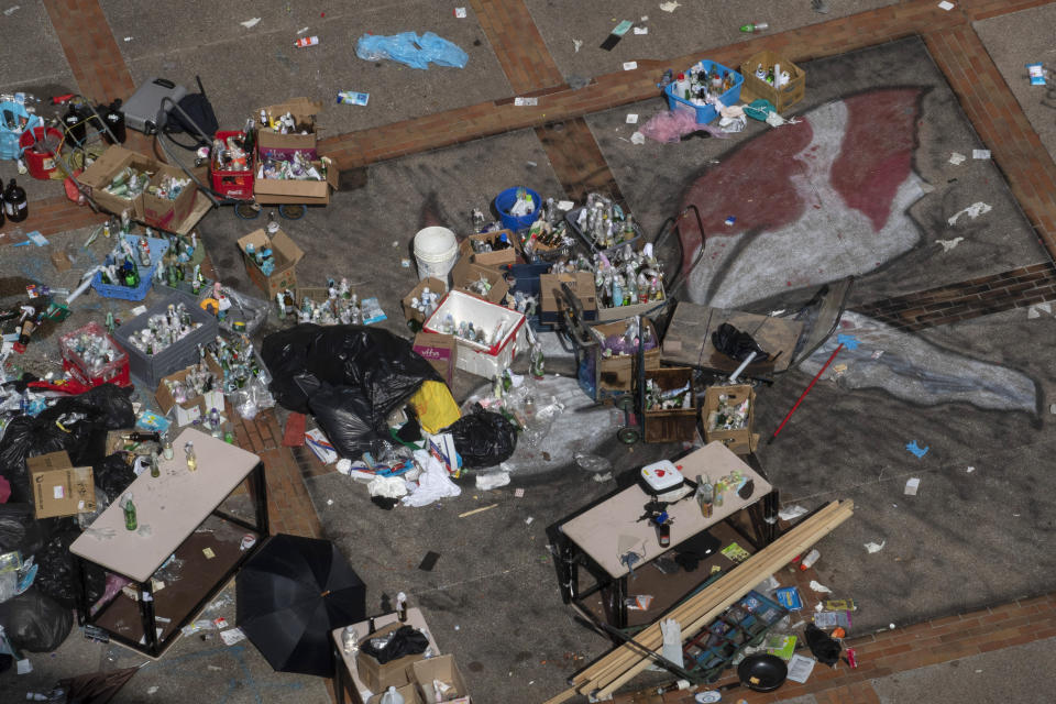 A Hong Kong flag painted on the ground of the Hong Kong Polytechnic University is partly covered up by a stockpile of Molotov cocktail in Hong Kong on Wednesday, Nov. 20, 2019. Hong Kong schools have reopened after a six-day shutdown but students were facing transit disruptions as the last protesters remained holed up on a university campus. (AP Photo/Ng Han Guan)