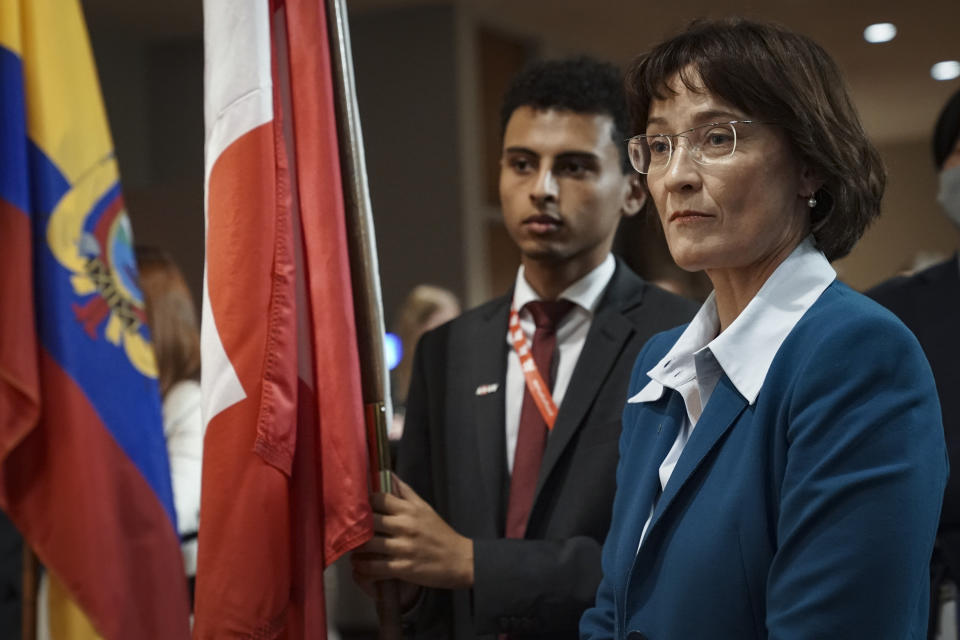 Diplomatic intern Naji Osman, left, holds the Switzerland national flag, as Switzerland's United Nations Ambassador Pascale Baeriswyl, right, prepares for its installation during a ceremony for five newly-elected non-permanent members to serving on the United Nations Security Council for the term 2023-2024, Tuesday Jan. 3, 2023 at U.N. headquarters. (AP Photo/Bebeto Matthews)