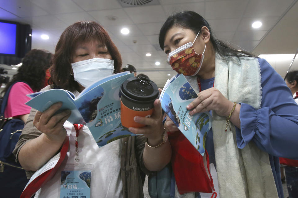 Taiwanese travelers, the first group of Palau-Taiwan Travel Corridor (travel bubble), look at tour summary before leaving Taiwan at Taoyuan International Airport in Taoyuan, northern Taiwan, Thursday, April 1, 2021. The Palau-Taiwan Travel Corridor, allowing people to travel between the islands without a COVID-19 quarantine, has started Thursday. (AP Photo/Chiang Ying-ying)